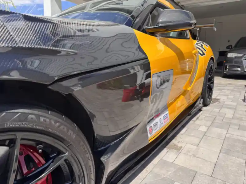 Glossy carbon fiber fender and yellow door on the Toyota GR Supra after detailing